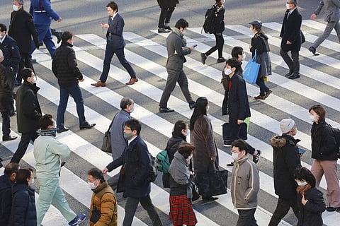 People wearing face masks to protect against the spread of the coronavirus cross an intersection on a street in Tokyo. (Photo | AP)