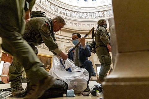 Rep. Andy Kim, D-N.J., helps ATF police officers clean up debris and personal belongings strewn across the floor of the Rotunda in the early morning hours of Thursday, Jan. 7 (Photo | AP)