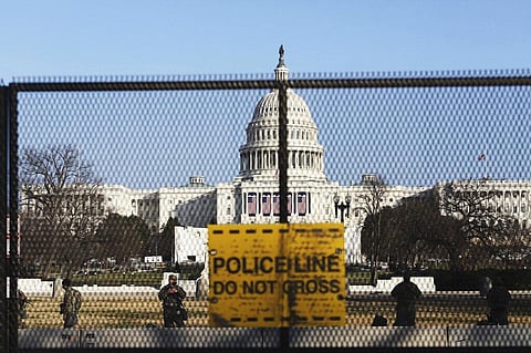 National guards are seen Wednesday, Jan. 13, 2021 on a fence that was erected to reinforce security at the Capitol in Washington. (Photo | AP)