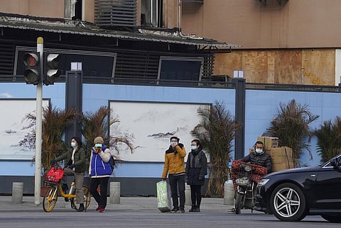 Residents wearing masks to protect from the coronavirus pass by the shutdown Huanan Seafood Market in Wuhan in central China. (Photo | AP)
