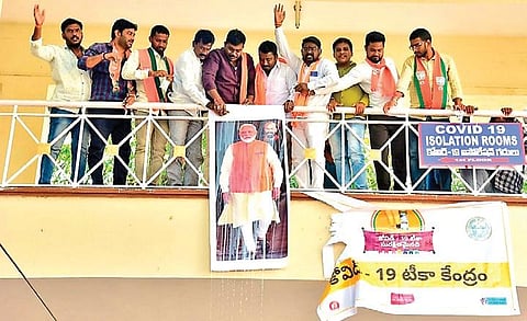 BJP workers erect flexis with the image of Prime Minister Narendra Modi after vandalising the ones with only Chief Minister K Chandrasekhar Rao’s image on them