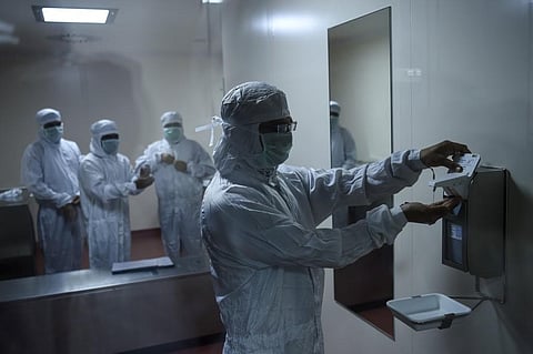 Employees prepare themselves before getting inside a lab where Covishield, AstraZeneca-Oxford's Covid-19 coronavirus vaccine is being manufactured, at India's Serum Institute. (Photo | AFP)