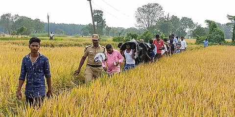 The police retrieving the body of the encountered police suspect Mahipal with a help of villagers through a paddy field in Erukkur near Sirkazhi. (Photo | EPS)