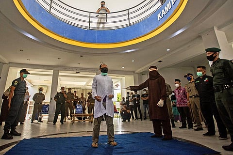 A Shariah Law official uses a rattan cane to whip one of two men convicted of gay sex in Indonesia. (Photo | AP)
