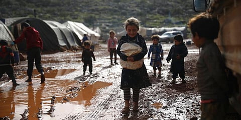 Syrian refugees walk through a camp for displaced muddied by recent rains near the village of Kafr Aruq , in Idlib province. (Photo | AP)