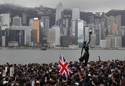 In this July 7, 2019, file photo, thousands of protesters carrying the British flag march near the harbor of Hong Kong. (Photo | AP)