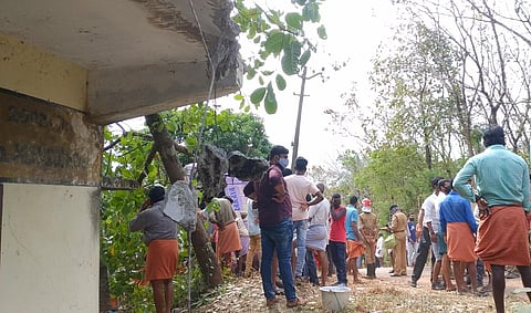 Local residents gather around the bus (right) that fell on a house at Pariyaram near Panathur in Panathady panchayat of Kasaragod on Sunday. (Photo | Express)