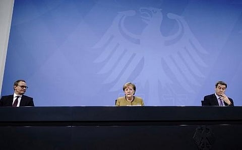 German Chancellor Angela Merkel (C) speaks next to Bavaria's State Premier Markus Soeder (R) and Berlin's Mayor Michael Mueller (L). (Photo | AFP)