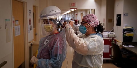 A nurse helps her colleague put on her personal protective equipment in a COVID-19 unit. (File photo | AP)