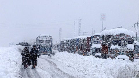 People walk past stranded vehicles on the Jammu-Srinagar National Highway