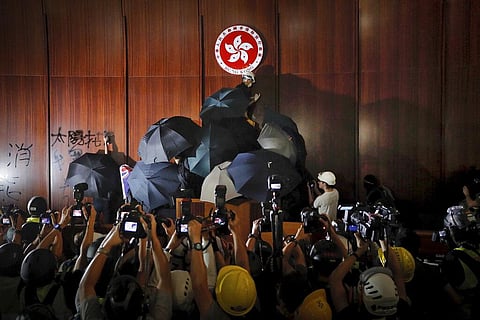 In this July 1, 2019, file photo, journalists photograph a protester defacing the Hong Kong emblem inside the meeting hall of the Legislative Council in Hong Kong. (Photo | AP)