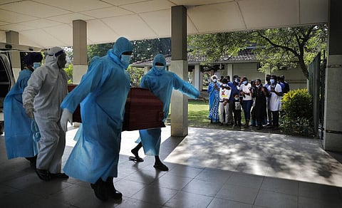 A Christian family grieves as municipal cemetery workers carry the body of their family member who died of COVID-19 for cremation in Colombo. (Photo | AP)