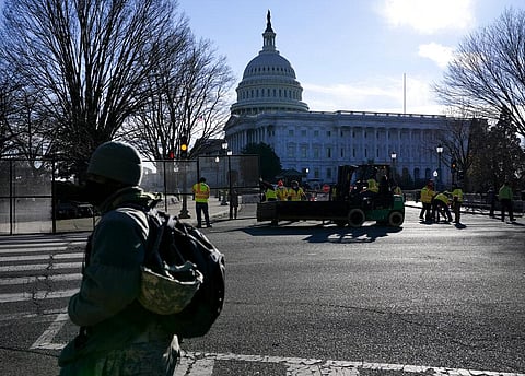 With the U.S. Capitol in the background, workers install fencing around the Capitol grounds the day after violent protesters loyal to President Donald Trump stormed the U.S. Congress. (Photo | AP)