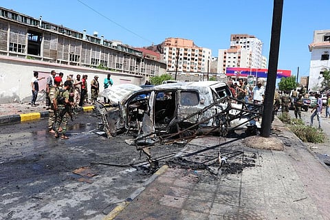 Security personnel stand amid the wreckage of a damaged vehicle at the site of a deadly car bomb attack. (Photo | AP)