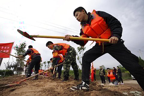 In this photo released by Xinhua News Agency, rescuer workers fortify a temporary dyke against the flooding at the Lianbo Village in Hejin City, in China's Shanxi Province, Sunday. (Photo| AP)