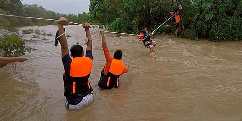 A resident is pulled along a rope as rescuers wait on the other side of a swollen river caused by heavy rains from Tropical Storm Kompasu in Gonzaga town, Cagayan province, Philippines. (Photo |AP)
