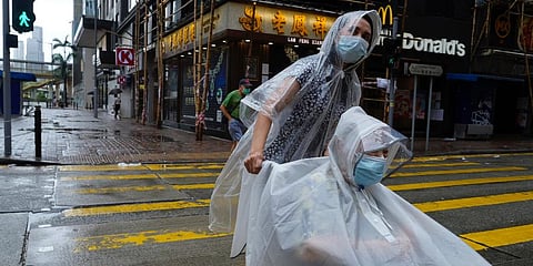 People make their way on an empty street as Typhoon Kompasu passes in Hong Kong. (Photo | AP)