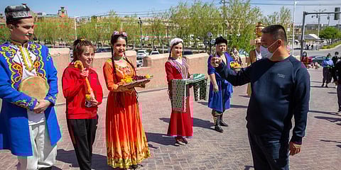A tourist snaps pictures of Uyghur performers in Kashgar city in China's far west Xinjiang region, during the welcome ceremony of a state tour for foreign media on April 19, 2021. (Photo | AP)