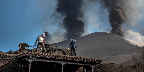 People clean up the ash off a house from the volcano in Las Manchas on the Canary island of La Palma, Spain on Thursday Oct. 14, 2021. (Photo | AP)