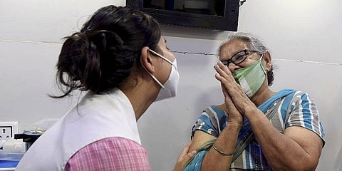 A beneficiary folding hands in gratitude to a health worker before receiving a dose of Covid vaccine in New Delhi. (File photo| PTI)