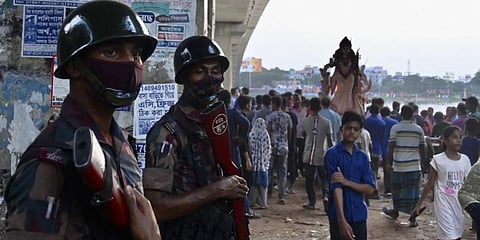 Border Guard Bangladesh personnel stand guard as Hindu devotees prepare to immerse an idol ofGoddess Durga in the Buriganga River on the final day of the Durga Puja festival in Dhaka. (Photo | AFP)