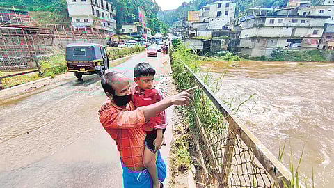 Suraj and father Vijayaraj watch the water level rising in Cheruthoni river after the authorities raised three shutters of the dam on Tuesday | EXPRESS