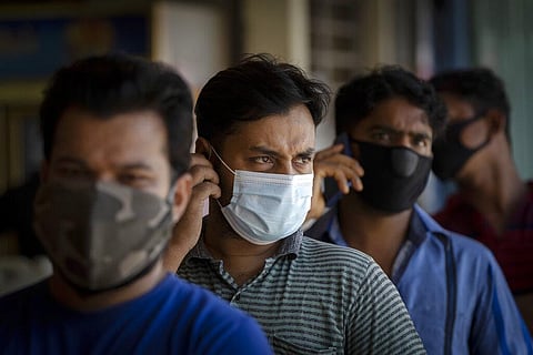 Foreign workers wearing face masks wait to be tested for COVID-19, at a wet market in Kuala Lumpur, Malaysia (Photo | AP)
