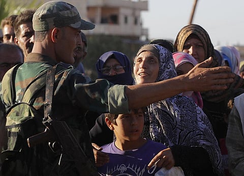 A woman talks with a soldier of the Syrian army during distribution of humanitarian aid from the Russian military in the town of Rastan, Syria (Photo | AP)