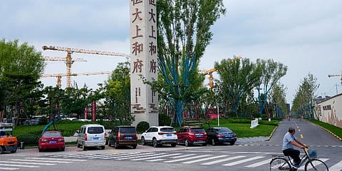 FILE - In this Sept. 15, 2021, file photo, a man bicycles past an Evergrande new housing development in Beijing. (Photo | AP)