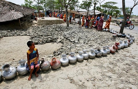 A girl sits on a vessel as she waits with others in a queue for water supplied by tankers at an area affected by last year's cyclone Aila in Nildumur. (Photo | AP)