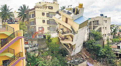 An excavator demolishing a tilted building in Bengaluru recently
