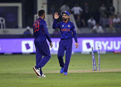 India Virat Kohli, right, speaks with teammate Varun Chakravarthy after an unsuccessful attempt to run-out Pakistan's Mohammad Rizwan. (Photo | AP)