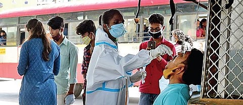 A health worker collects swab samples of a passenger at Kempegowda Bus Station in Bengaluru on Sunday. (Photo | Shriram BN)