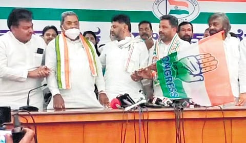 KPCC president DK Shivakumar hands over the Congress flag to party candidate Ashok Managuli, as Leader of the Opposition Siddaramaiah, and senior leaders MB Patil and Eshwar Khandre look on, in Sind