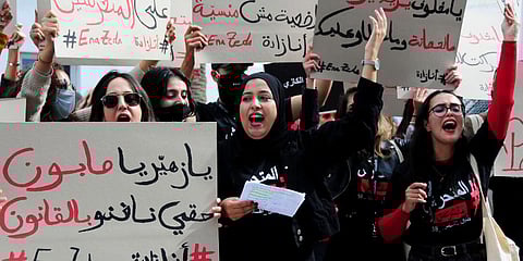 A woman holds a poster reading 'I can use the law against him', left, during a protest outside the court house in Nabeul, Tunisia. (Photo | AP)
