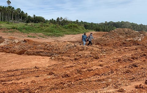Residents walk through the pathway along the acquired land for Vizhinjam Port at Mulloorthottam.