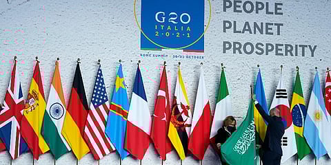 Workers adjust a flag prior to a group photo at the G20 summit in Rome, Saturday, Oct. 30, 2021. (Photo | AP)