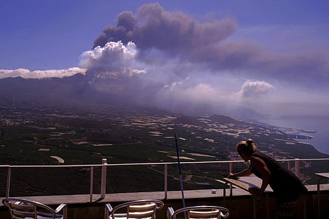A worker cleans the ash from the tables of a restaurant as lava flows from a volcano on the Canary island of La Palma, Spain on Monday Oct. 4, 2021. (Photo | AP)