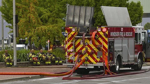 Firefighters take a break by the Ambassador Bridge border crossing in Windsor, Ontario. ( Photo | AP)