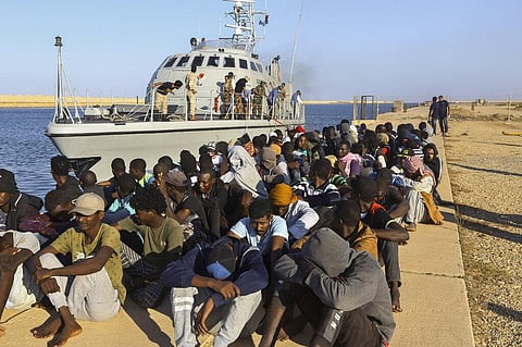 In this Tuesday, Oct. 1, 2019 file photo, rescued migrants are seated next to a coast guard boat in the city of Khoms, Libya. (Photo | AP)