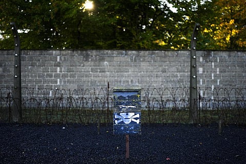 A warning sign stands in front of barbed wire and a wall inside the former Sachsenhausen Nazi death camp in Oranienburg, Germany. (Photo | AP)