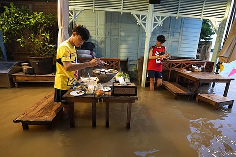 Customers of the riverside Chaopraya Antique Café enjoy themselves despite the extraordinary high water levels in the Chao Phraya River near Bangkok. (Photo | AP)
