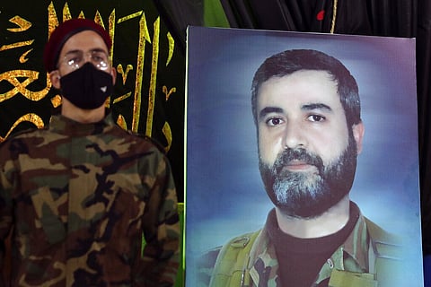 Hezbollah fighter stands next to a picture of Ali Atwa, a senior Hezbollah operative, during his funeral procession in the southern Beirut suburb of Dahiyeh, Lebanon. (Photo | AP)
