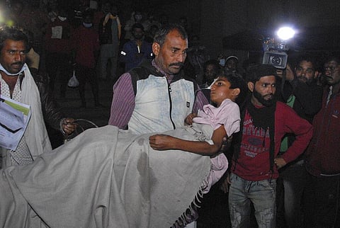 A man carries a child out from the Kamla Nehru Children’s Hospital after a fire in the newborn care unit of the hospital killed four infants. (Photo | AP)