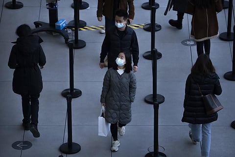 People wearing face masks to protect against COVID-19 wait in line to enter a store at an outdoor shopping center in Beijing, Saturday, Nov. 13, 2021. (Photo | AP)