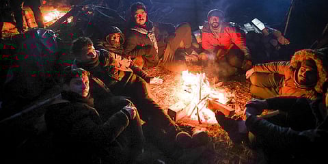 Migrants warm themselves near fire gathering at the Belarus-Poland border near Grodno, Belarus. (Photo | AP)