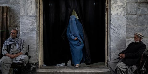 A woman leaves a Shiite shrine in a predominantly Hazara neighborhood while two men stand guard in Kabul, Afghanistan, Tuesday, Nov. 9, 2021. (Photo | AP)