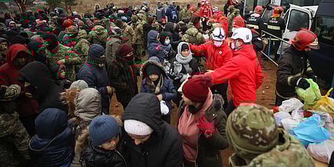 Belarusian Red Cross employees hand over humanitarian aid to migrants from the Middle East and elsewhere gathering at the Belarus-Poland border near Grodno, Belarus. (Photo | AP)
