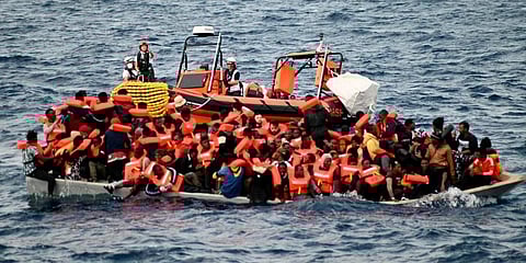 An overcrowded wooden boat packed with 99 migrants is approached by a tender of the humanitarian organization off the Libya coast. (Photo | AP)