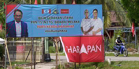 A motorist passes by an election campaign banner in a local village in Malacca, Malaysia, Monday, Nov. 8, 2021. (Photo | AP)